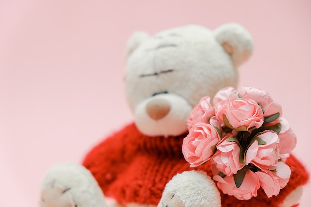 Foto fondo del día de san valentín. lindo osito de peluche con ramo de flores.