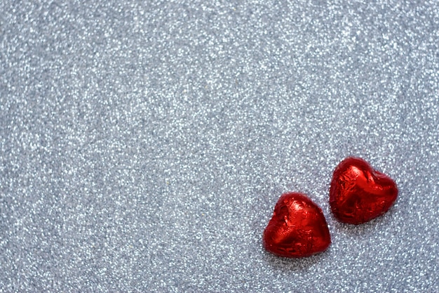 Fondo del día de San Valentín, maqueta con dos caramelos de chocolate con forma de corazón rojo