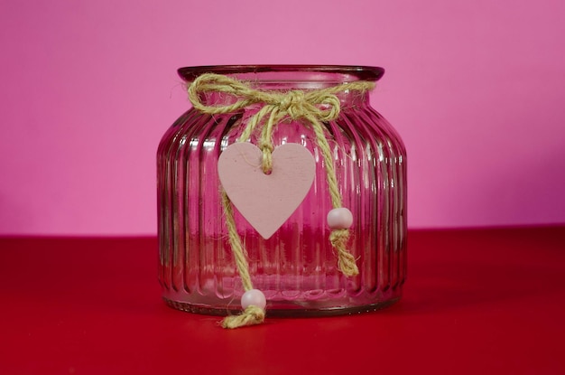 Fondo del día de San Valentín. Rosa roja en un jarrón de cristal sobre un fondo rosa.