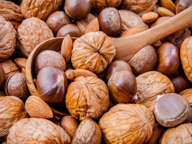 Fondo con diferentes tipos de frutos secos con cuchara de madera.