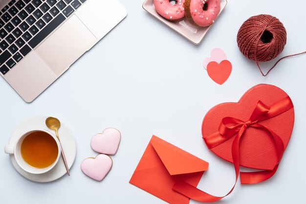 Foto fondo de escritorio de san valentín con regalo de corazón rojo, computadora portátil y té. tarjeta de felicitación del día de san valentín.