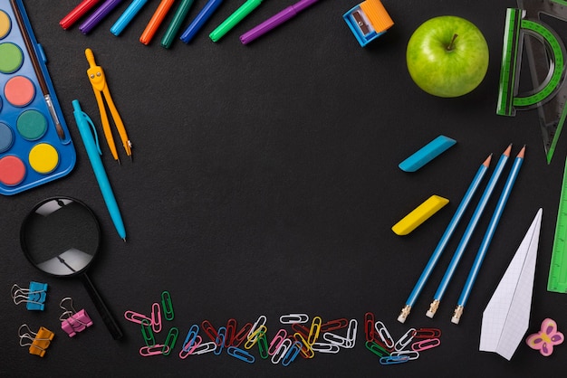 Fondo de escuela de pizarra negra con útiles escolares y artículos de papelería