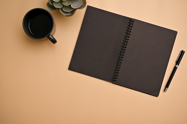 Fondo de espacio de trabajo beige naranja mínimo con cuaderno espiral negro vacío