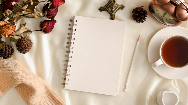 Fondo de espacio de trabajo femenino con cuaderno espiral vacío flores secas sobre fondo blanco