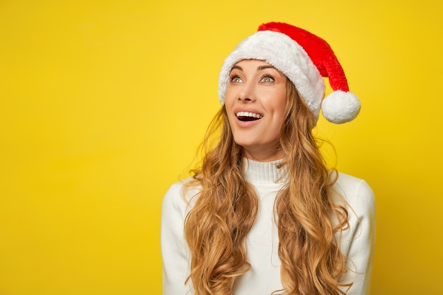 Fondo de estudio amarillo de suéter de sombrero de santa de navidad de mujer