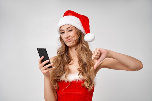 Fondo de estudio de mujer Navidad Santa Hat blanco con smartphone en mano