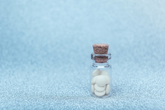 Fondo farmacéutico médico con pastillas blancas en una botella de vidrio. Medicamento de farmacia para la salud. Píldora de la felicidad.