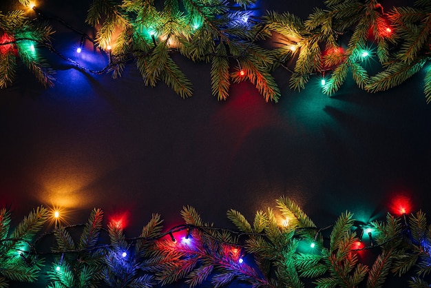 Fondo de feliz Navidad con espacio de copia de texto. Concepto de año nuevo. Luces de hadas brillantes y decoración de ramas de abeto. Endecha plana, vista superior