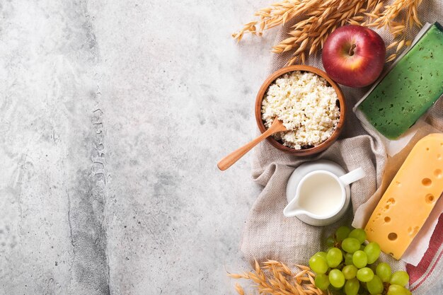 Fondo feliz de Shavuot para la celebración de Shavuot Leche y queso trigo maduro y frutas fondo de madera azul Productos lácteos sobre fondo de hormigón de mesa gris antiguo Concepto de Shavuot Maqueta