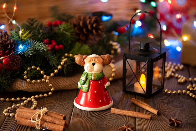 Fondo festivo de Navidad con un ciervo de juguete vestido como árbol de Navidad de Santa Claus decorado con decoración con luces doradas fondo festivo en un primer plano de la mesa de madera