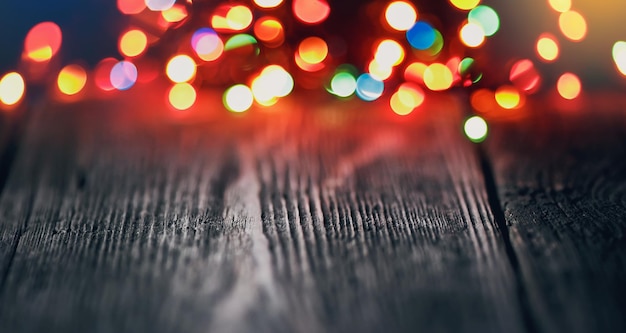 Fondo festivo con puntos de luz y bokeh frente a una mesa de madera vacía