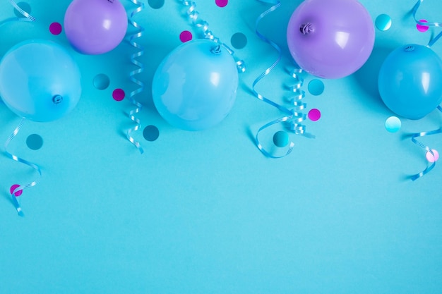 Fondo de fiesta con serpentinas de globos y confeti sobre fondo azul pastel