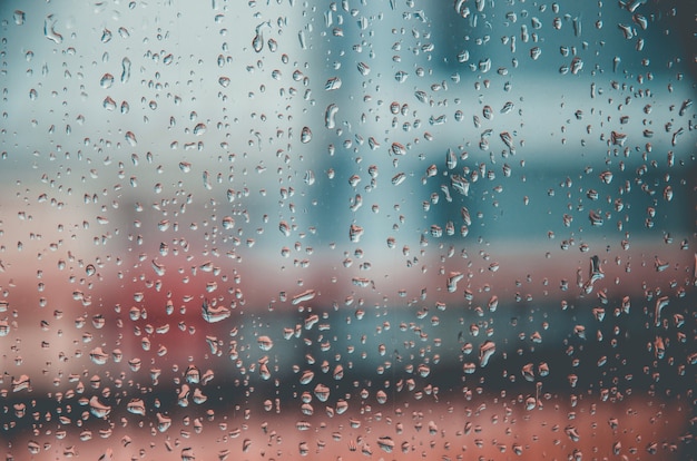 Fondo y fondo de pantalla por gota de lluvia y gotas de agua en el cristal de la ventana.