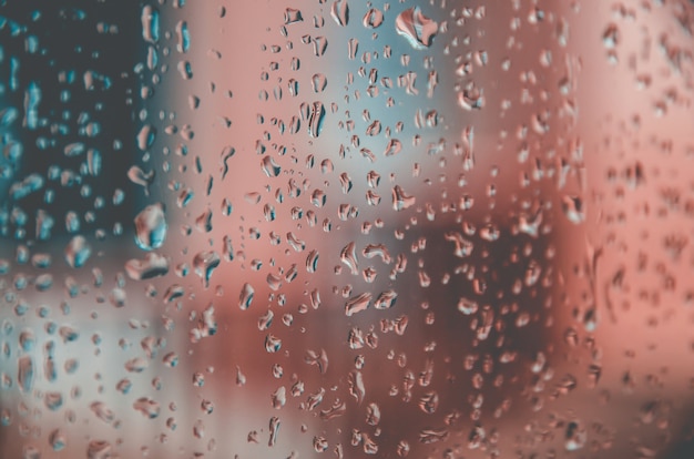 Fondo y fondo de pantalla por gota de lluvia y gotas de agua en el cristal de la ventana.