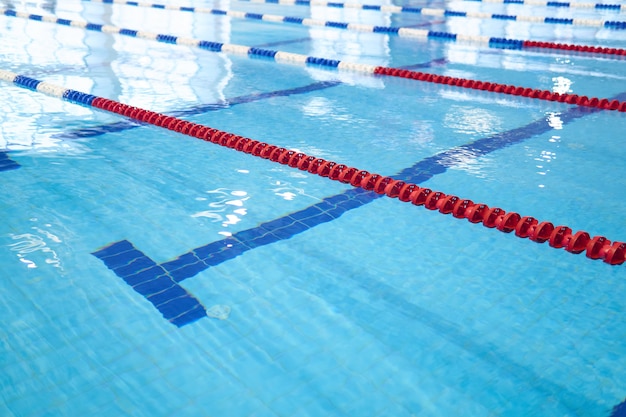 Fondo: fragmento de la piscina de competición con agua azul y carriles de natación marcados