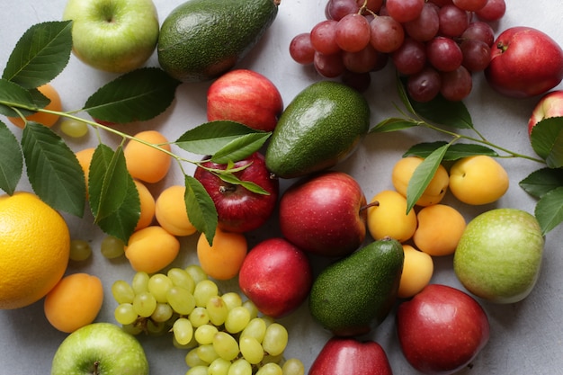 Fondo de frutas con manzanas, uvas, albaricoques, duraznos y aguacate