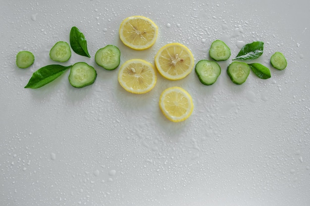 Fondo de frutti fresco rodajas de pepino y limón crudo sobre fondo blanco.