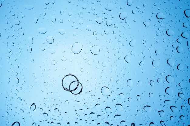 Fondo gotas de agua y dos anillos en el cristal