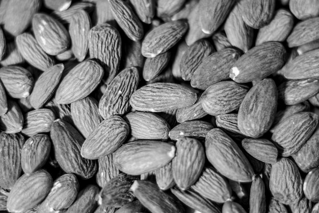 Fondo de grandes almendras peladas crudas situadas arbitrariamente Fondo de grandes almendras peladas crudas en blanco y negro