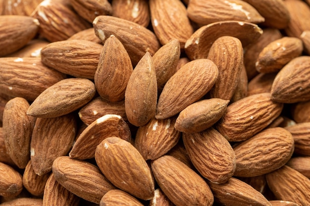 Fondo de grandes almendras peladas crudas, tiro macro de nueces sabrosas frescas orgánicas, refrigerio delicioso natural, cocinar ingredientes para hornear. Primer plano de la textura de las nueces. Concepto de comida vegetariana saludable, espacio de texto