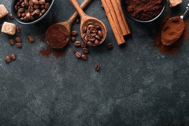 Fondo de granos de café Concepto de café tostado con diferentes tipos de granos de café y palitos de canela sobre fondo de piedra negra oscura Vista superior Concepto de café Maqueta