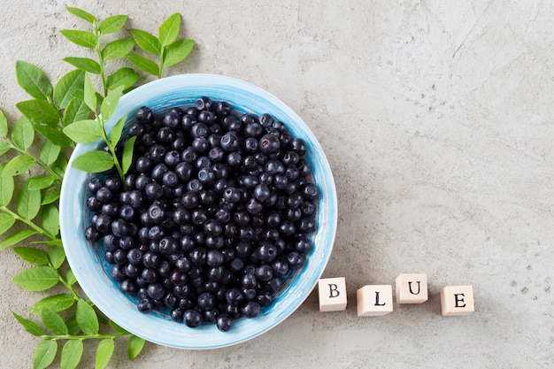 en un fondo gris bayas de arándanos en un plato de cerámica azul, la palabra azul