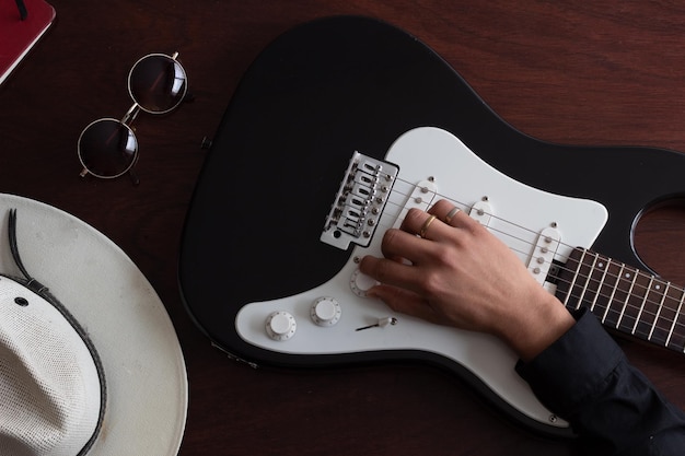 Fondo de una guitarra eléctrica en una mesa de madera y la mano del músico en la guitarra