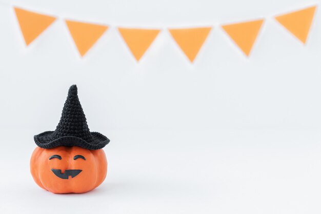 Fondo de Halloween de calabaza con sombrero negro con cara divertida en una superficie gris de vacaciones