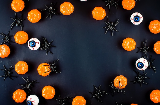 Fondo de Halloween con muchas calabazas, ojos de caramelo y arañas en negro, concepto de vacaciones de otoño, cosecha, espacio de copia, vista superior, maqueta