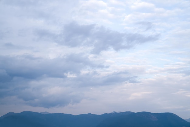 Fondo de hermosas nubes esponjosas de color blanco grisáceo sobre una banda de picos montañosos