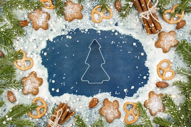 Fondo de invierno de Navidad Galletas de jengibre picantes pretzels harina Espacio de copia Pizarra y ramas de abeto de nieve