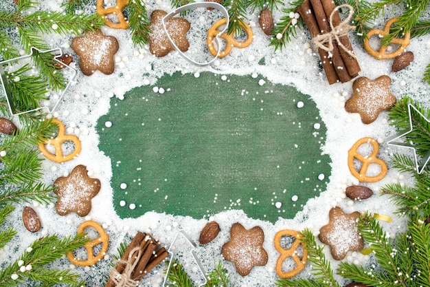 Fondo de invierno de Navidad Galletas de jengibre picantes pretzels harina Espacio de copia Pizarra y ramas de abeto de nieve