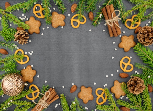 Fondo de invierno de Navidad Galletas de jengibre picantes pretzels harina Espacio de copia Pizarra y ramas de abeto de nieve