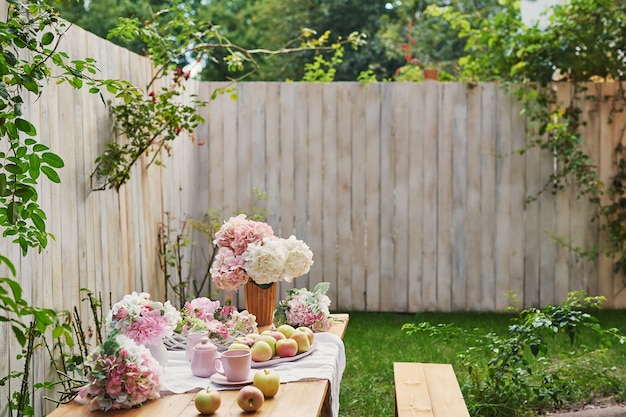 Fondo de jardín de verano. Ramo de flores hortensias y taza de té en la mesa. Buenos dias acogedor. Picnic en la naturaleza. Tarjeta de felicitación del día de la madre. Celebracion