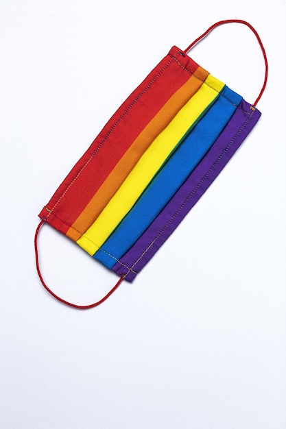 Fondo LGBT con mascarilla protectora de color arco iris desde arriba. Endecha plana. virus del COVID-19