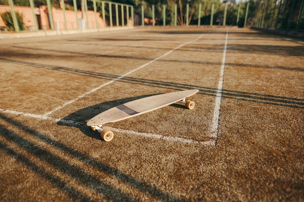 Fondo Longboard se encuentra en una vieja cancha de tenis Concepto de patinaje Concepto de patinaje