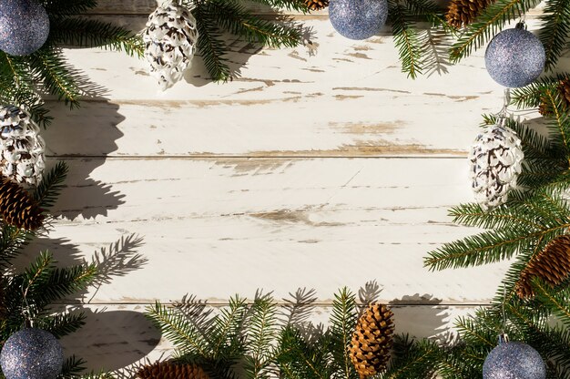 Fondo de madera blanca con decoración navideña de ramas de abeto verde, conos naturales y juguetes navideños. vista superior. una copia del espacio.