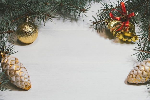 Fondo de madera blanca de Navidad con rama de pino, bolas de oro, conos, campanas, espacio de copia