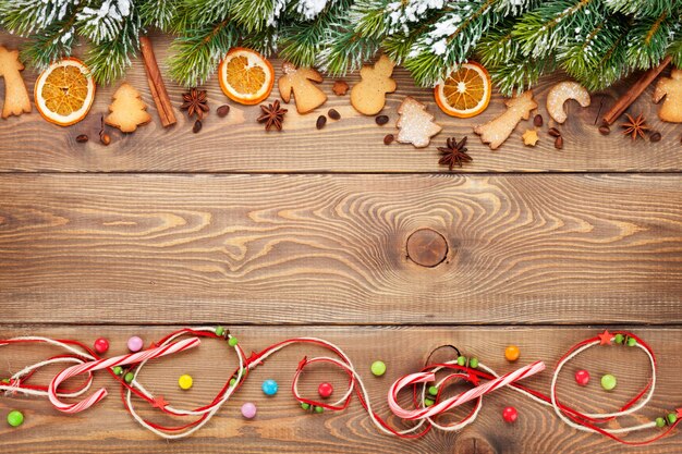 Fondo de madera de navidad con nieve abeto especias galletas de jengibre y dulces