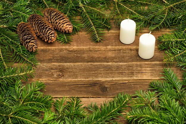 Fondo de madera con ramas de abeto, conos y velas.