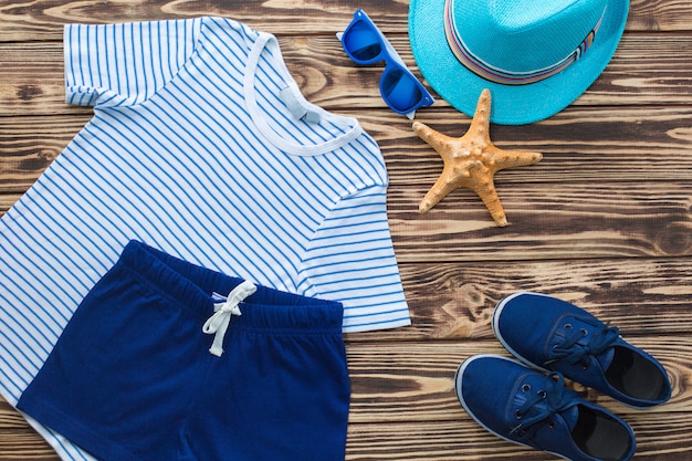 Fondo del mar Cosas del `s del niño en un fondo de madera. Todavía plana de ropa infantil.