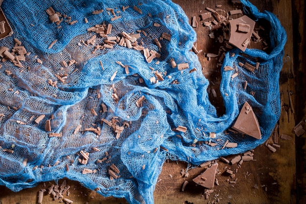 Fondo marrón y azul con barra de chocolate y textil.