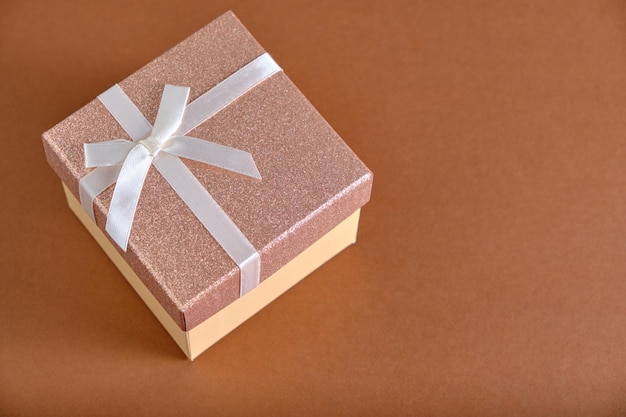 El fondo marrón de la caja de regalo está atado con una cinta beige con lazo