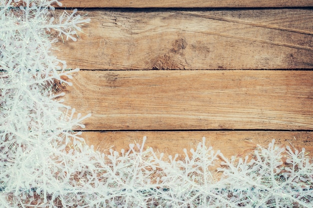 Fondo marrón de madera de la Navidad y copos de nieve blancos con el espacio.