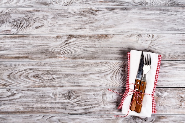 Fondo de mesa de madera vacía y tenedor y cuchillo en la servilleta. Concepto de cena, almuerzo o desayuno.