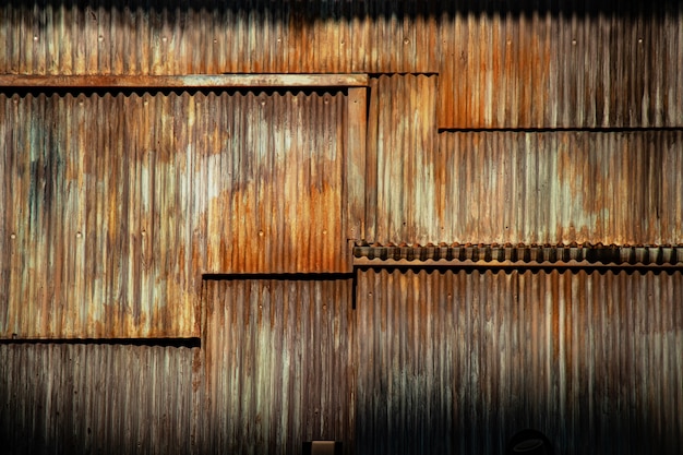 Fondo de metal corrugado de textura grunge oscuro, superficie del acero oxidado, área decaída de la pared de los barrios marginales