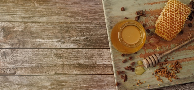 Fondo de miel Dulce miel en un frasco de vidrio y una cuchara de miel en una mesa de madera Banner Copiar espacio para su texto