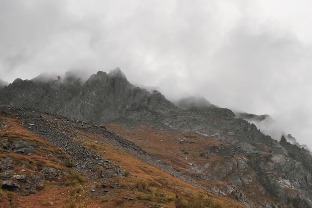 Fondo místico con montañas dramáticas Lluvia en las montañas Paisaje brumoso atmosférico con siluetas borrosas de rocas afiladas en nubes bajas durante la lluvia