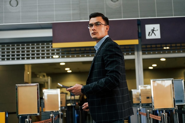 Foto fondo moderno joven empresario en ropa formal está en el aeropuerto durante el día