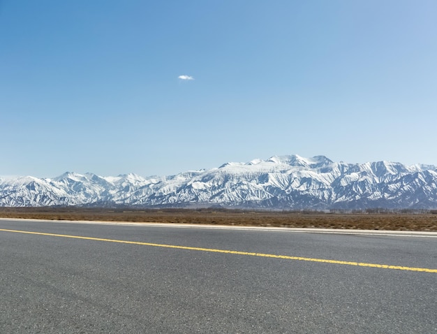 Fondo de montaña de nieve con carretera asfaltada vacía en la ciudad China de golmud